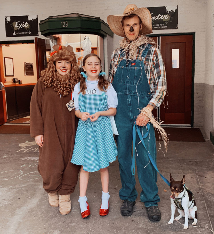 Weekend Reads #129 1 a woman dressed as the cowardly lion, young girl dressed as Dorothy Gale, man dressed as a scarecrow holding onto the leash of a small dog