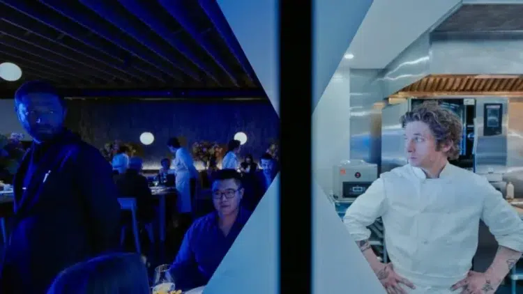 scene from season 3 of the bear where you see Carmy in the kitchen and on the other side of the wall a bustling darkly lit restaurant with Cousin standing in it.