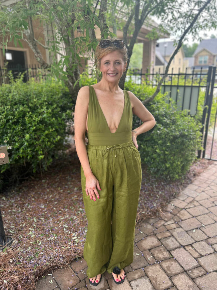 Woman in a olive green plunging one piece swimsuit from Monday Swimwear with matching linen drawstring trousers