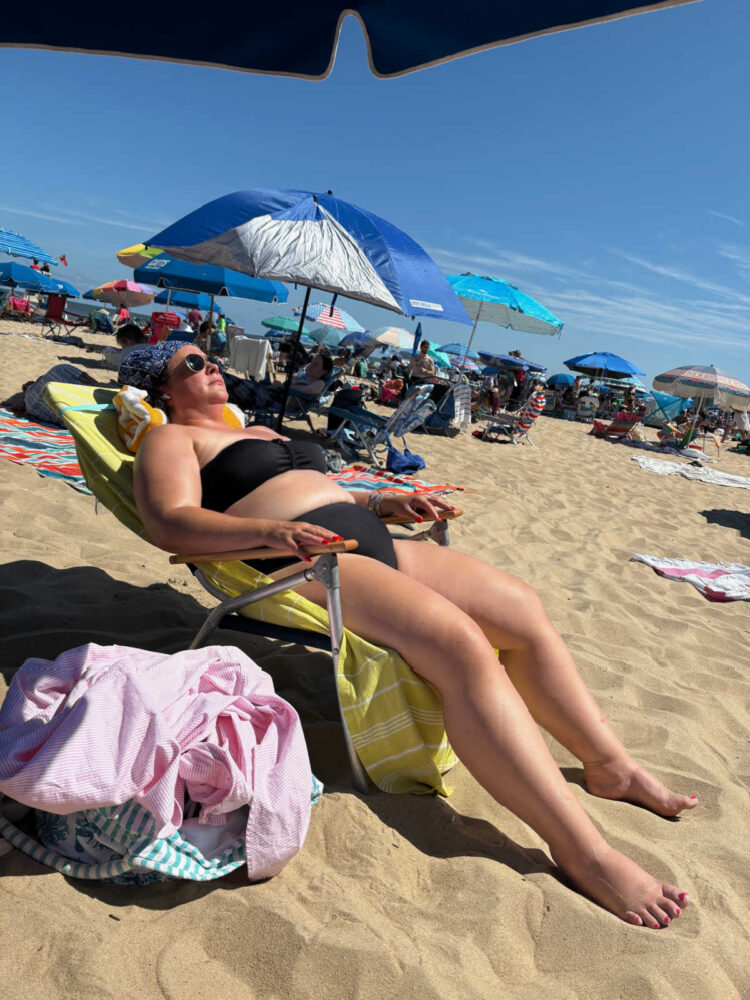 Woman lying on the beach in a black bikini | 2025 Rehoboth Beach