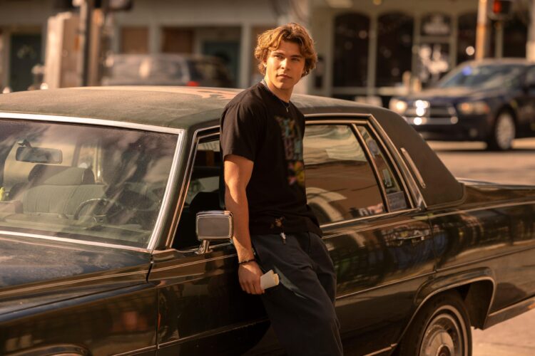 Charlie Cooper in The Runarounds leaning against his car, a Cadillac Fleetwood