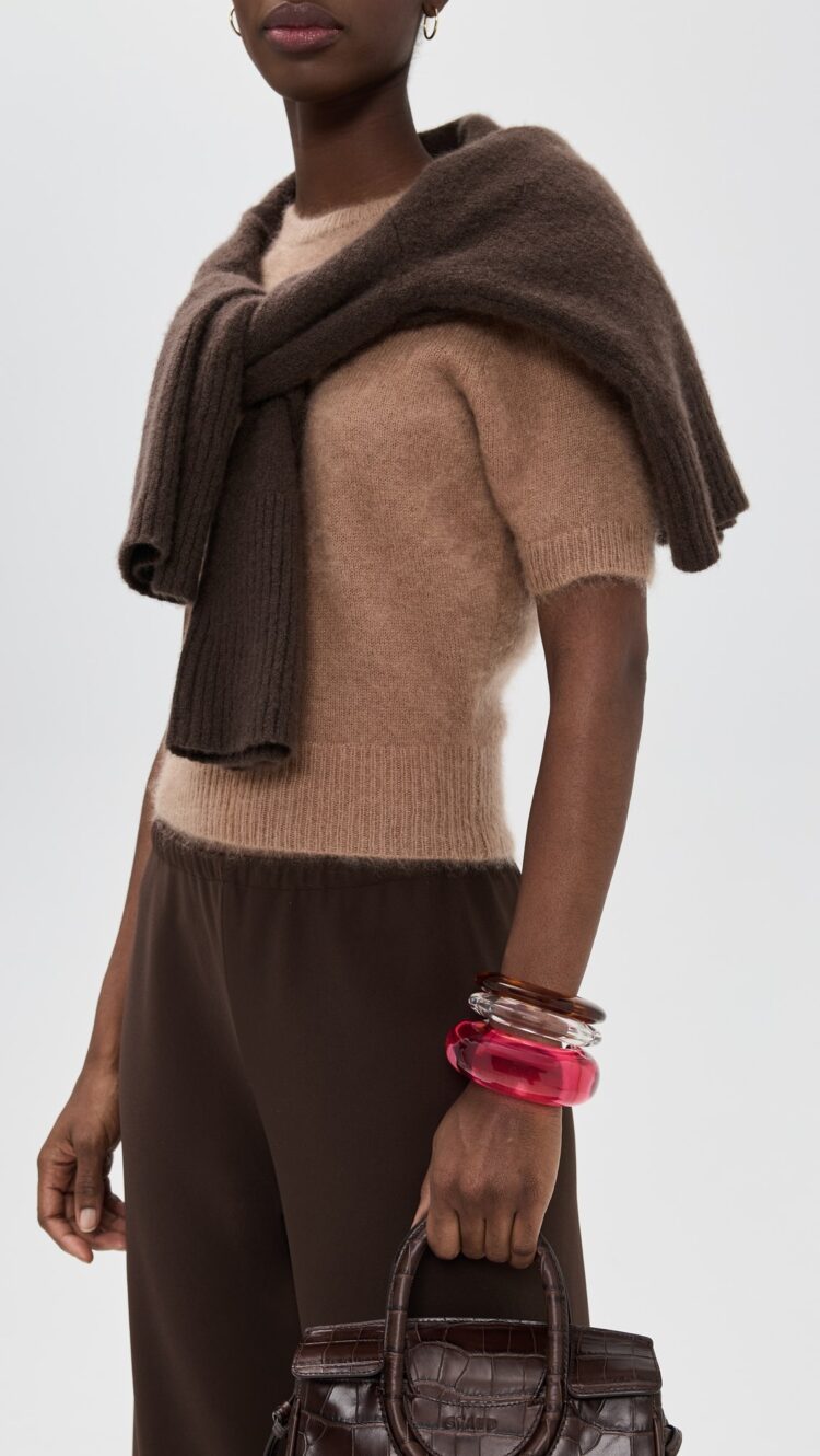 a model wearing three bangles in pink, clear, and brown