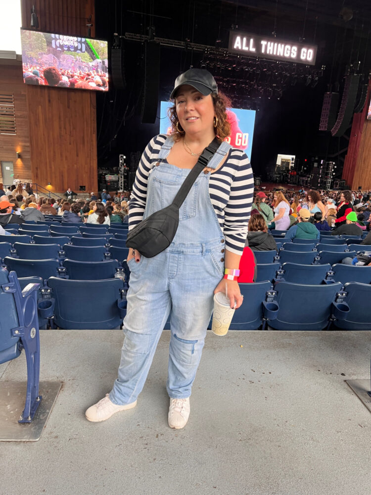 Woman at the All Things Go festival wearing a striped shirt, overalls, and a belt bag as a crossbody